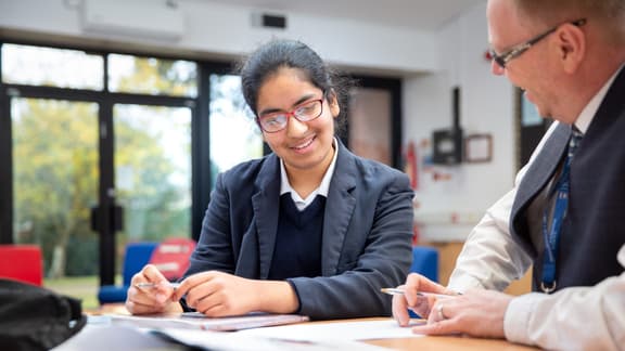 Student studing at desk with teacher
